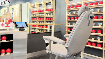 a chair in a room with a mirror and shelves with red balls