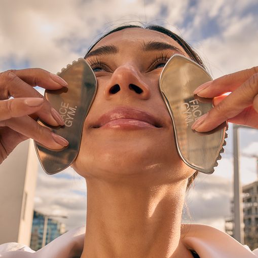 a woman holding up two metal objects over her face