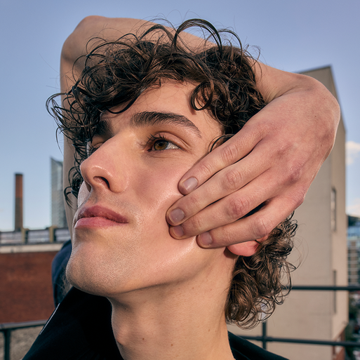 a man with curly hair holding his hand on his face